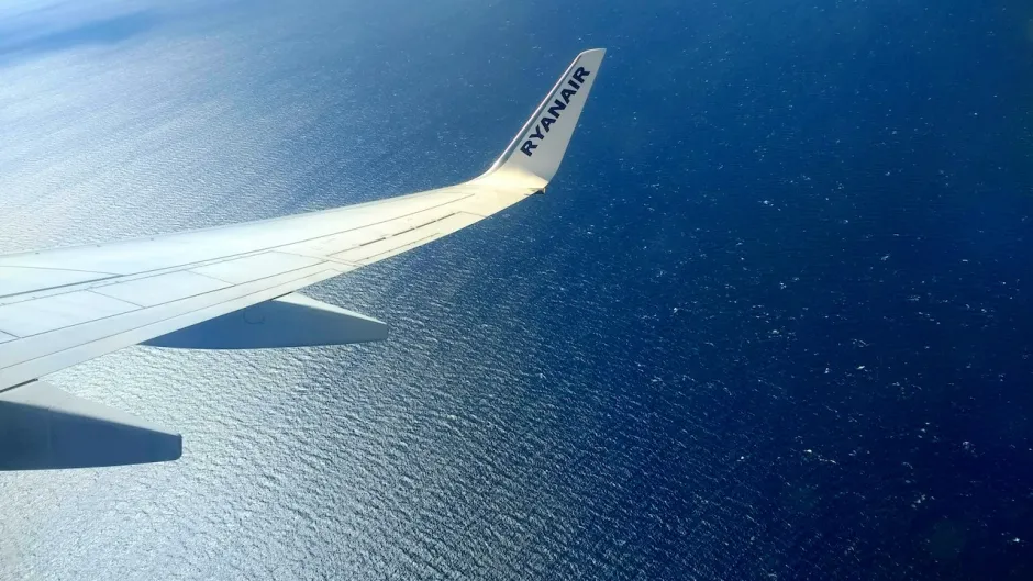 Ein Flugzeug des Billigfluganbieters Ryanair fliegt über einem Meer oder Ozean.
